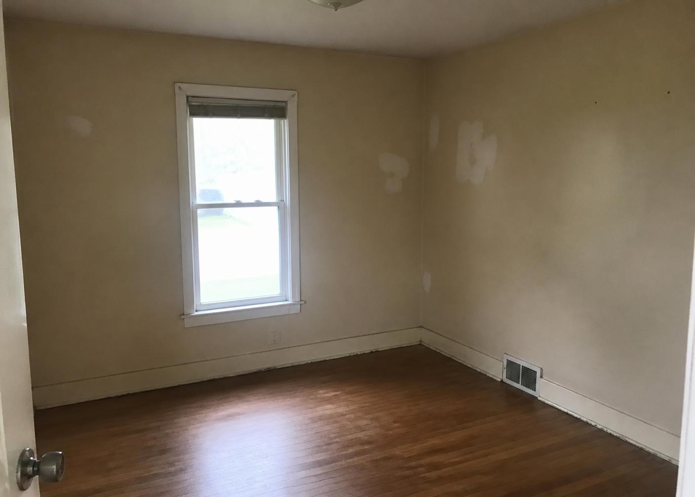 Bedroom before repaint: scuffed, patchy walls and worn trim